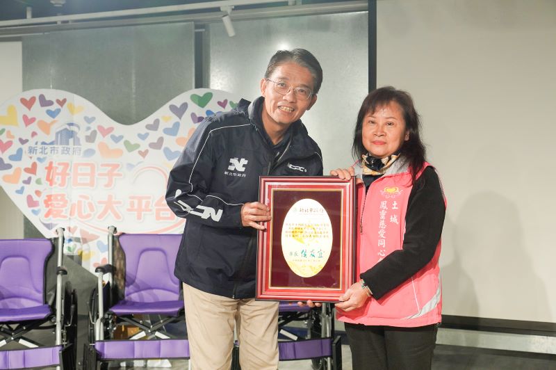 《圖說》新北市府秘書長邱敬斌（左）代表侯友宜市長回贈感謝牌給土城鳳靈慈愛同心會理事長黃妙鳳。〈社會局提供〉